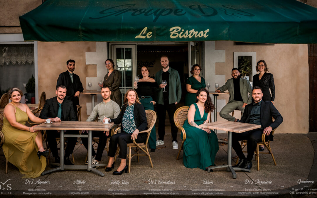 13 collaborateurs et collaboratrices prennent la pose à la terrasse d'un bistrot provençal pour vous souhaiter une bonne année 2026 !